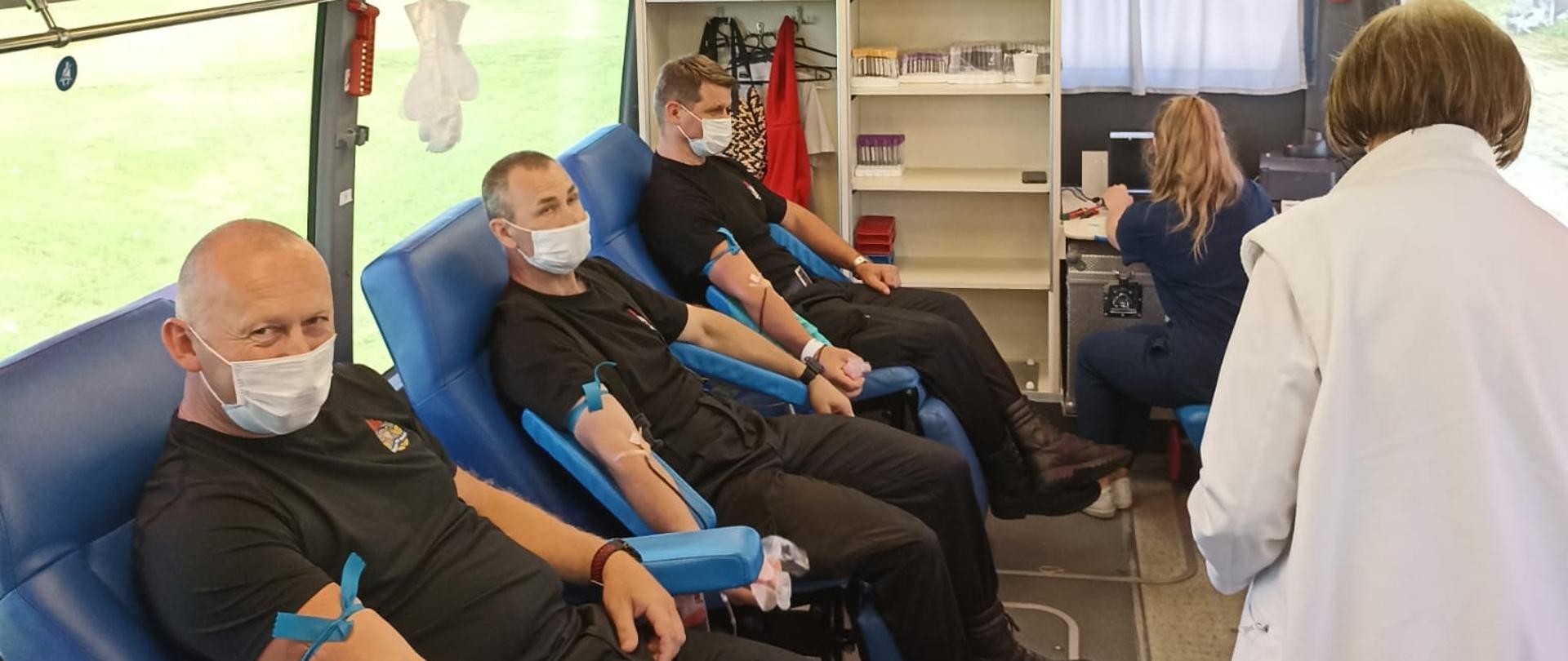 Strażacy oddający krew w krwiobusie