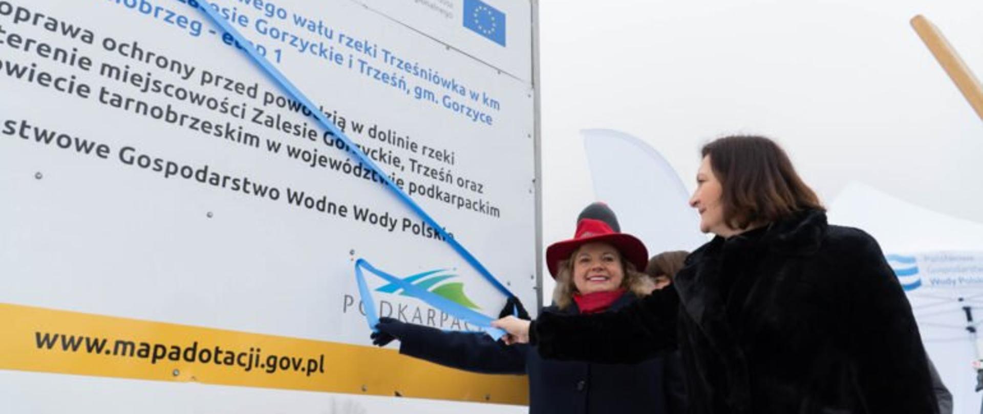 Wojewoda podkarpacki Ewa Leniart i wicemarszałek województwa podkarpackiego Ewa Draus przecinają wstęgę przy tablicy z nazwą inwestycji