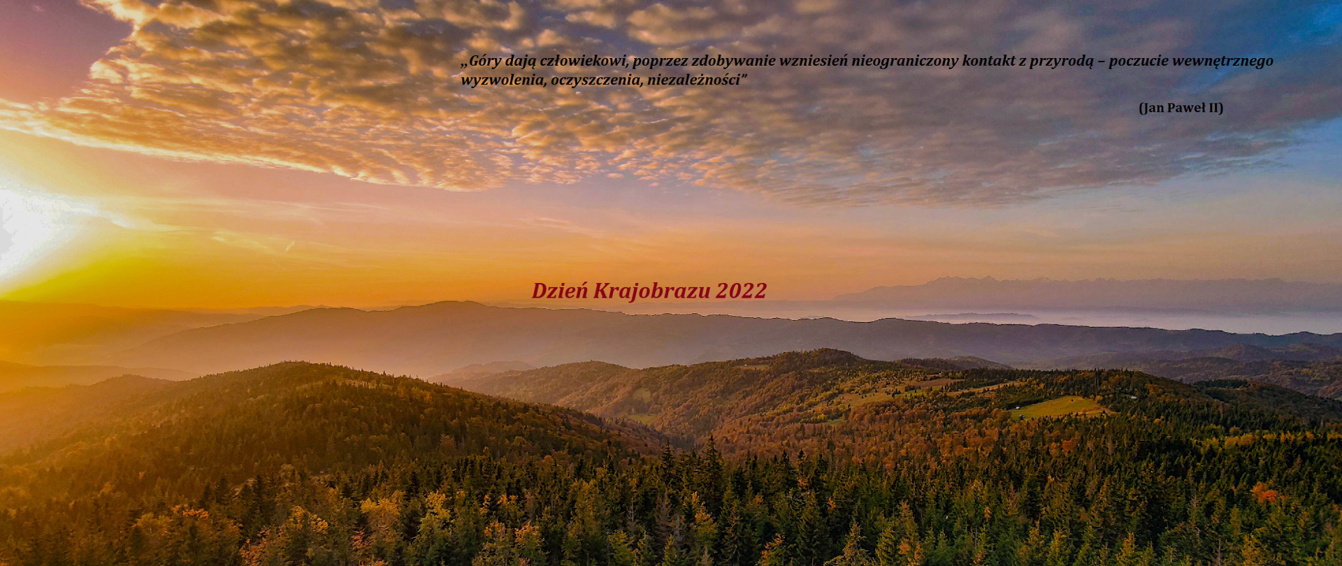 Na pierwszym planie zalesione wzgórza, w prawym rogu słońce tuż nad horyzontem. W oddali zamglone doliny. Na środku napis Dzień krajobrazu 2022.