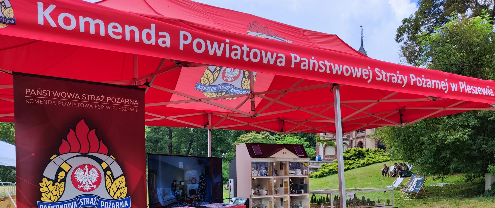 Stoisko pleszewskiej straży podczas festiwalu lasu. Mobilny symulator zagrożeń oraz baner straży pożarnej.