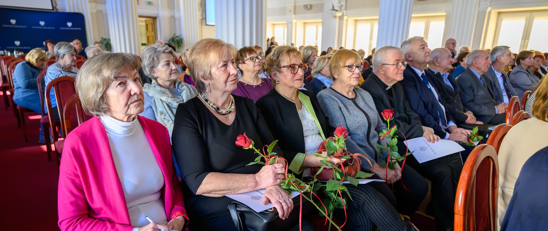Zdjęcie przedstawia seniorów biorących udział w uroczystości z okazji jubileuszu Uniwersytetów Trzeciego Wieku