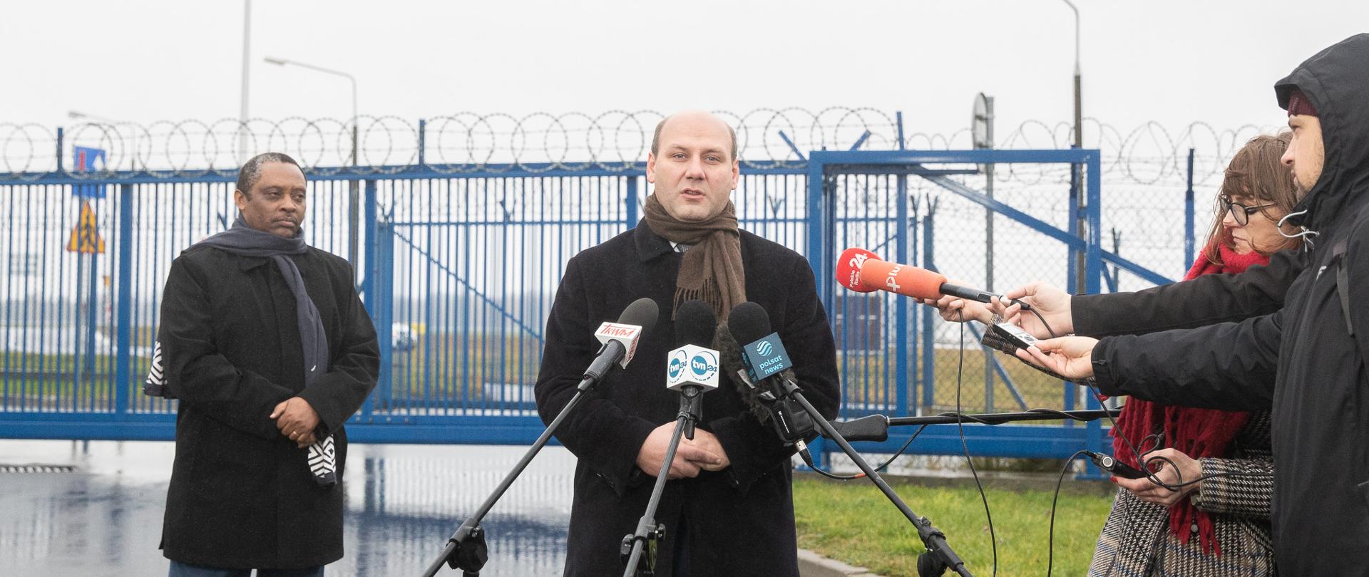 Mężczyzna mówi do ustawionych przed nim mikrofonów