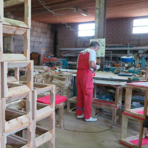 mężczyzna stoi przy stole i trzyma w ręku narzędzie 