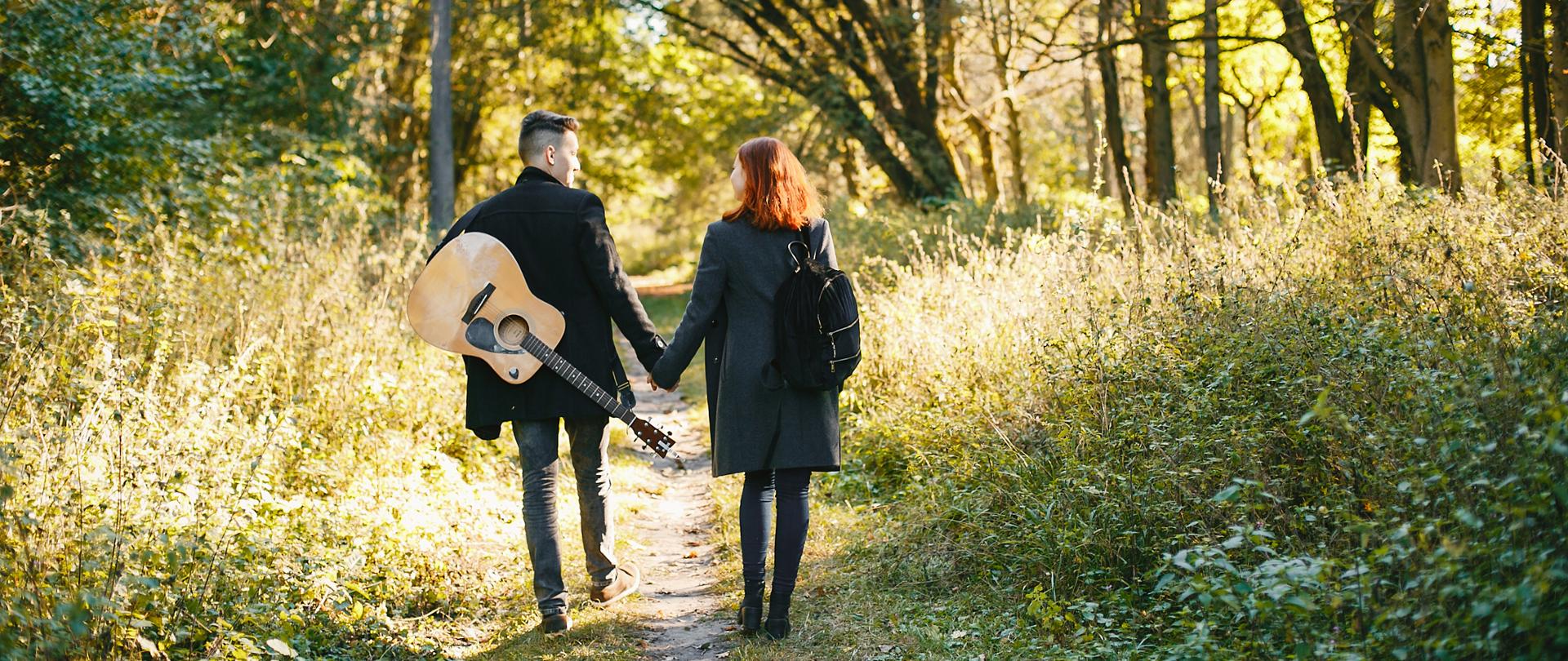 Cute couple in a park. Lady with red hair. Guy with a guitar