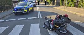 Motocykl leży na drodze, po lewej samochód policji