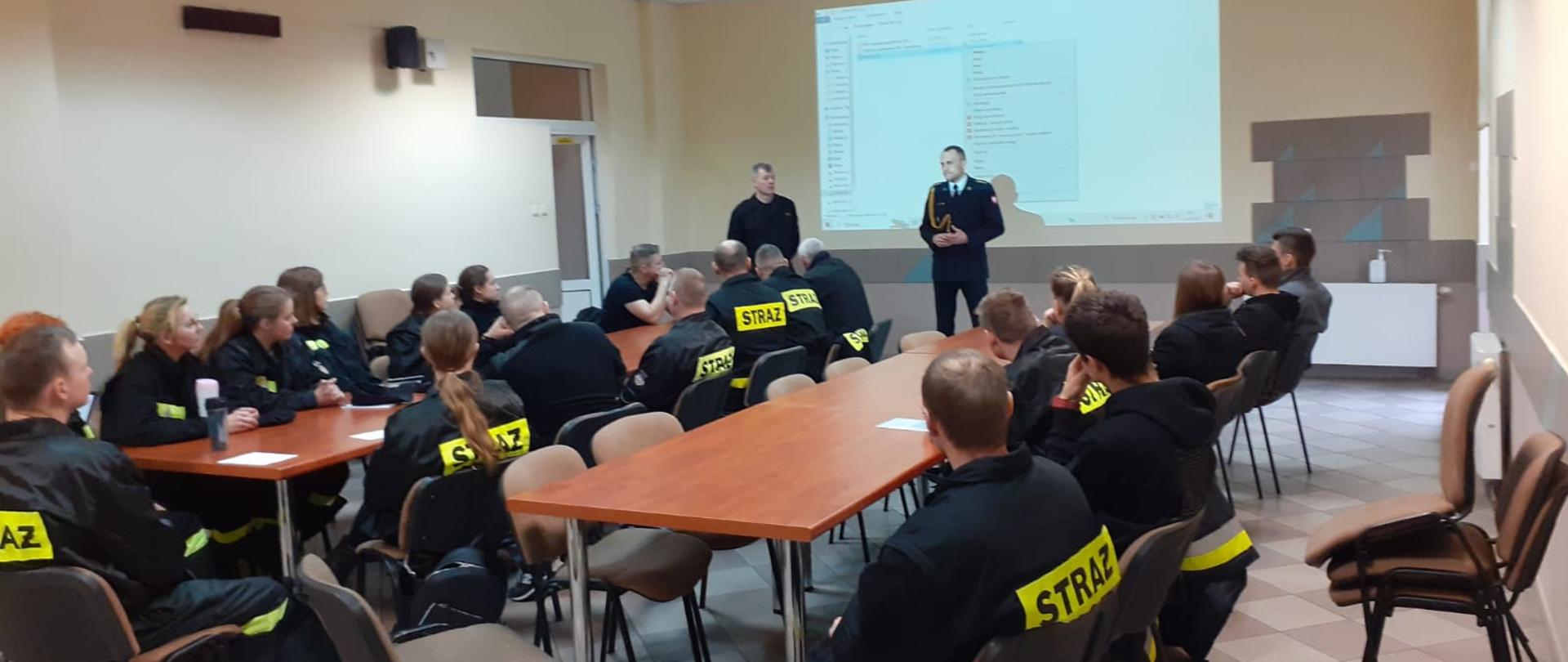 Uczestnicy szkolenia oraz wykładowcy siedzą przy stołach w trakcie szkolenia.