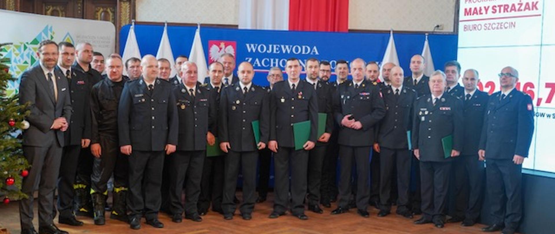 Zdjęcie grupowe uczestników spotkania. W tle ścianka prezentacyjna wojewody zachodniopomorskiego.