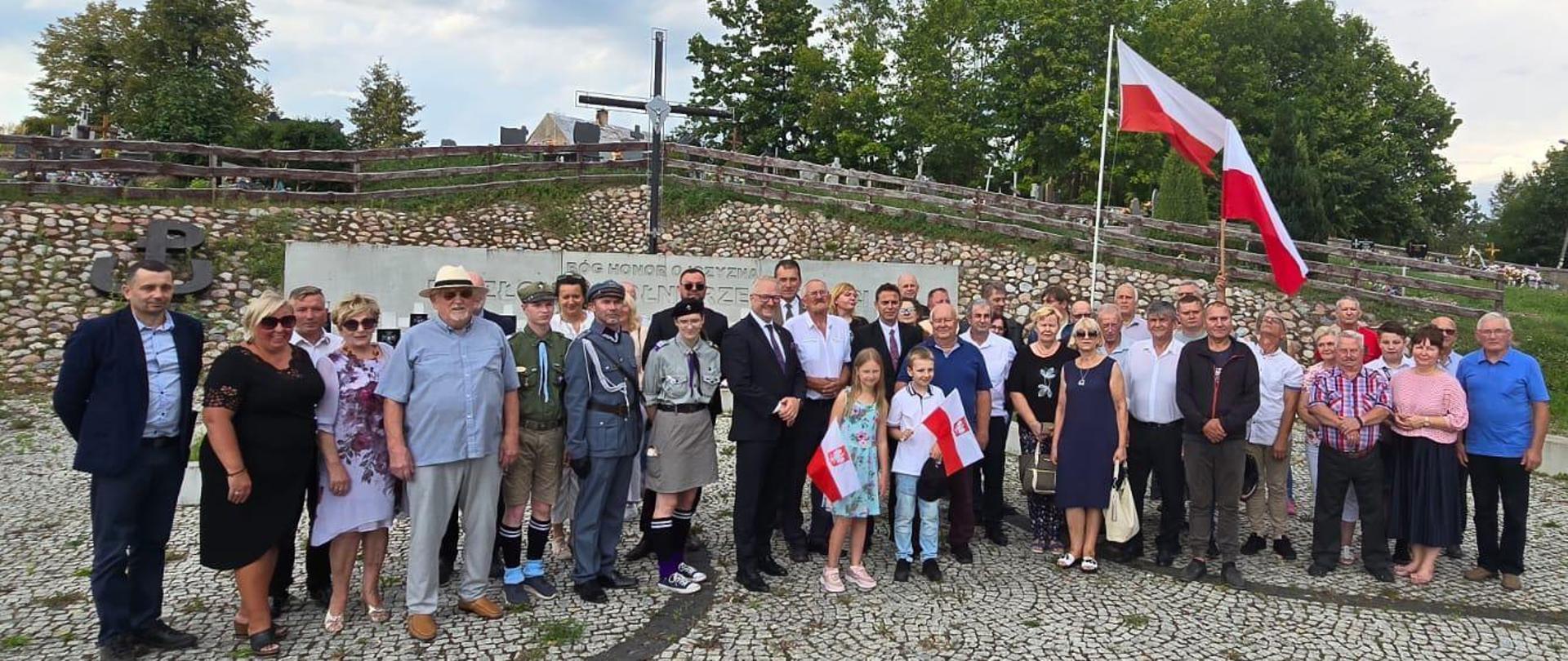 Pamiątkowa fotografia wykonana na uroczystości obchodów Święta Wojska Polskiego w Orłowie - 17 sierpnia 2024 r. Na pierwszym planie widać grupę ludzi, w tle powiewają biało-czerwone flagi. 