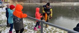 Strażak uczący dziecko rzucić linę ratowniczą dla tonącej osoby