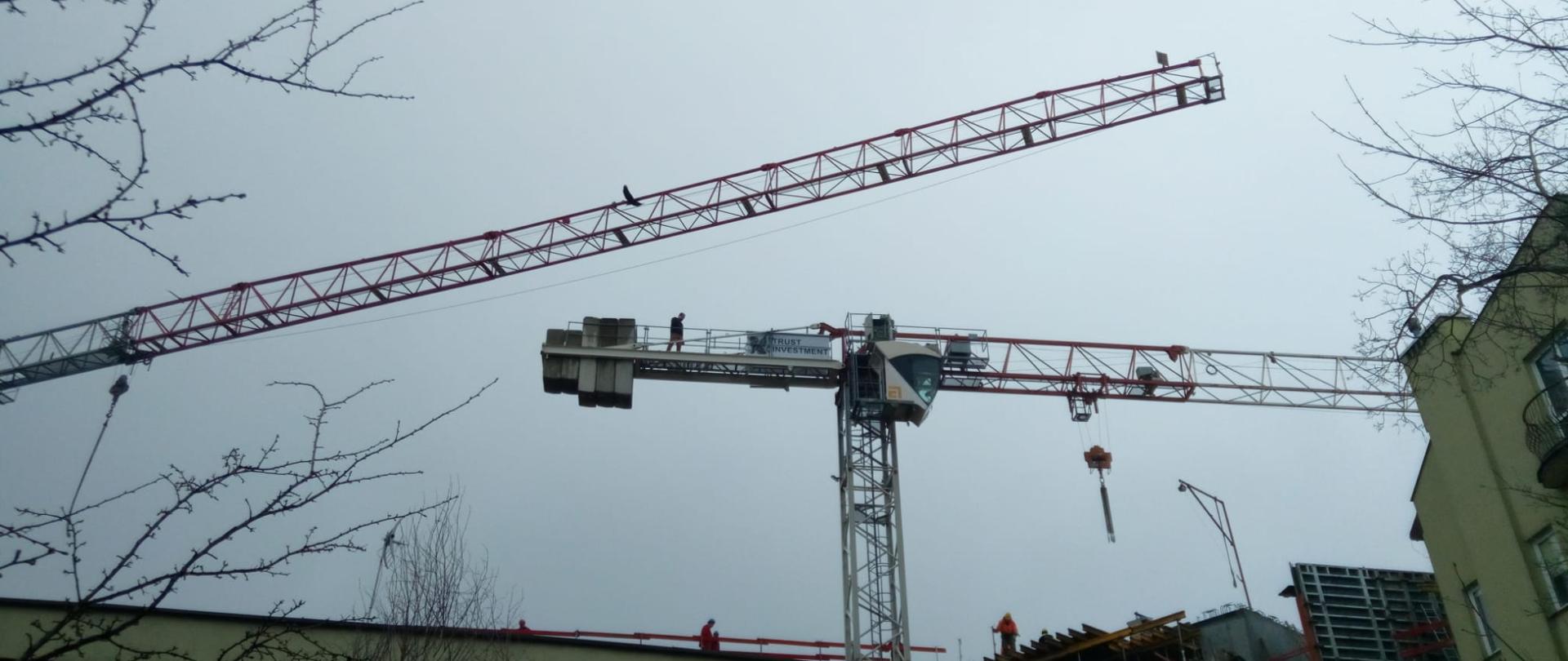 Zdjęcie przedstawia dwa żurawie budowlane nad nowo powstającymi budynkami. Na jednym z nich doszło do pożaru.