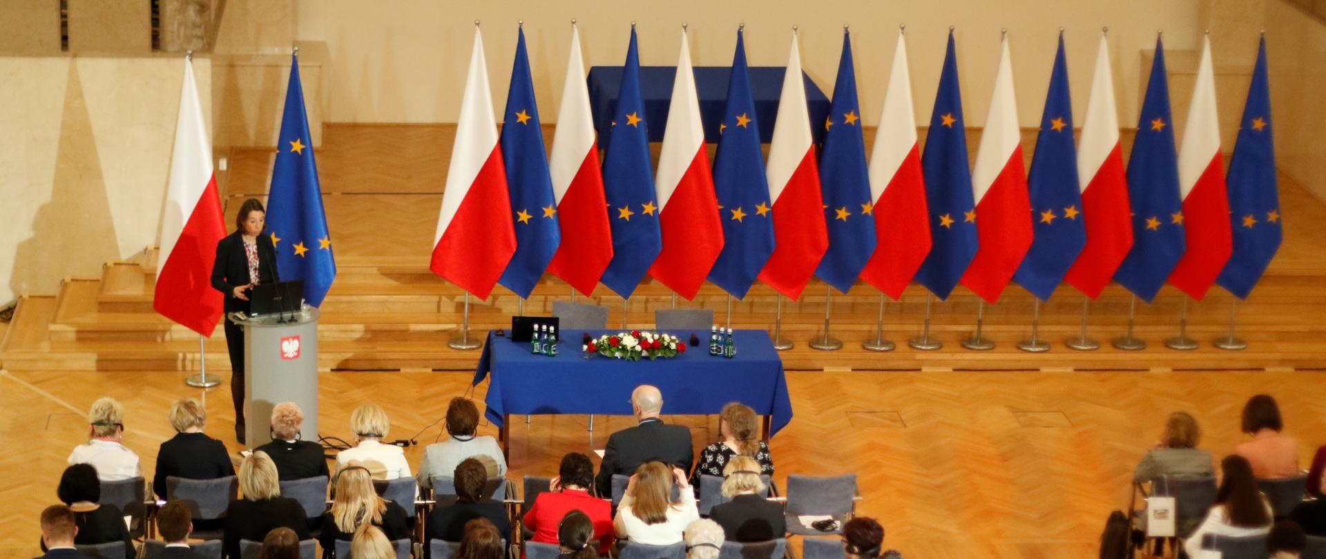 Widok sali w Kancelarii Premiera z gór. W tle flagi Polski i Unii Europejskiej
