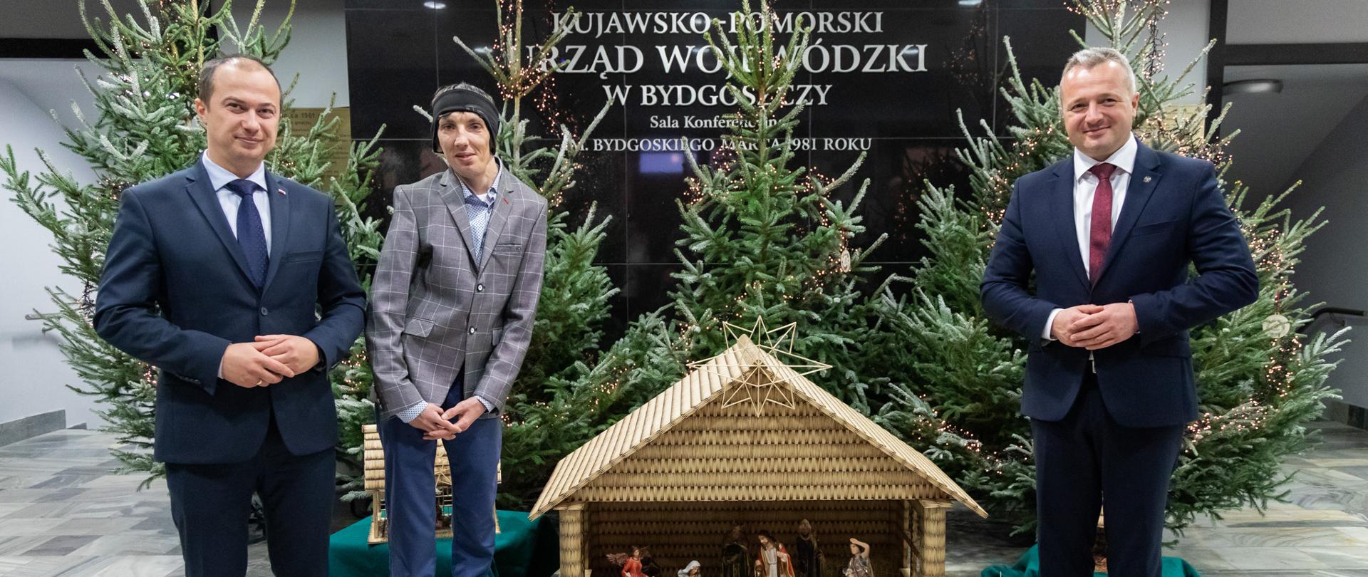 Bożonarodzeniowa szopka wykonana z zapałek i stojący przy niej artysta oraz wojewodowie