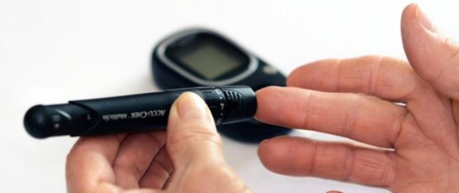 Osoba badając sobie poziom cukru za pomocą czarnego glukometru