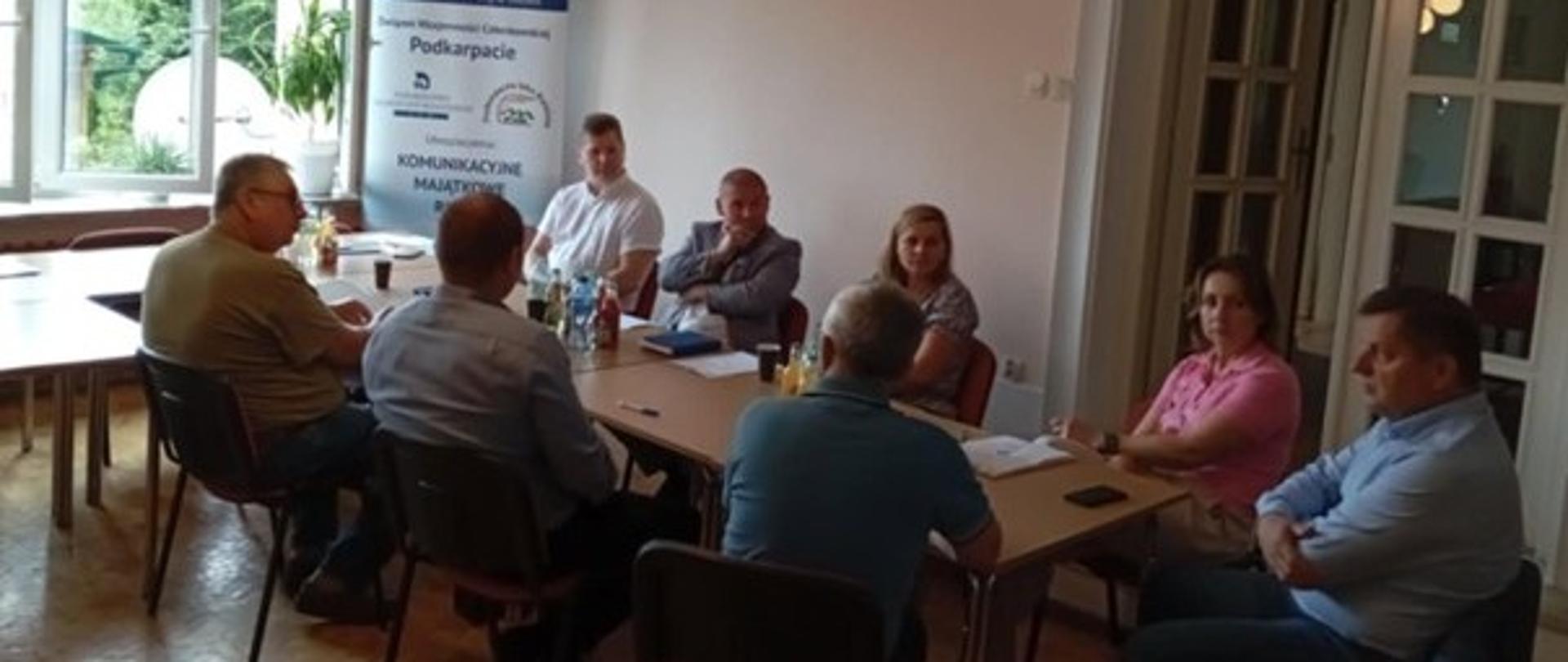 Grupa ludzi siedząca przy stole. 