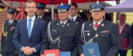 mężczyzna w garniturze, wicewojewoda, oraz 2 mężczyzn w mundurze pozują do zdjęcia z wuróżnieniami