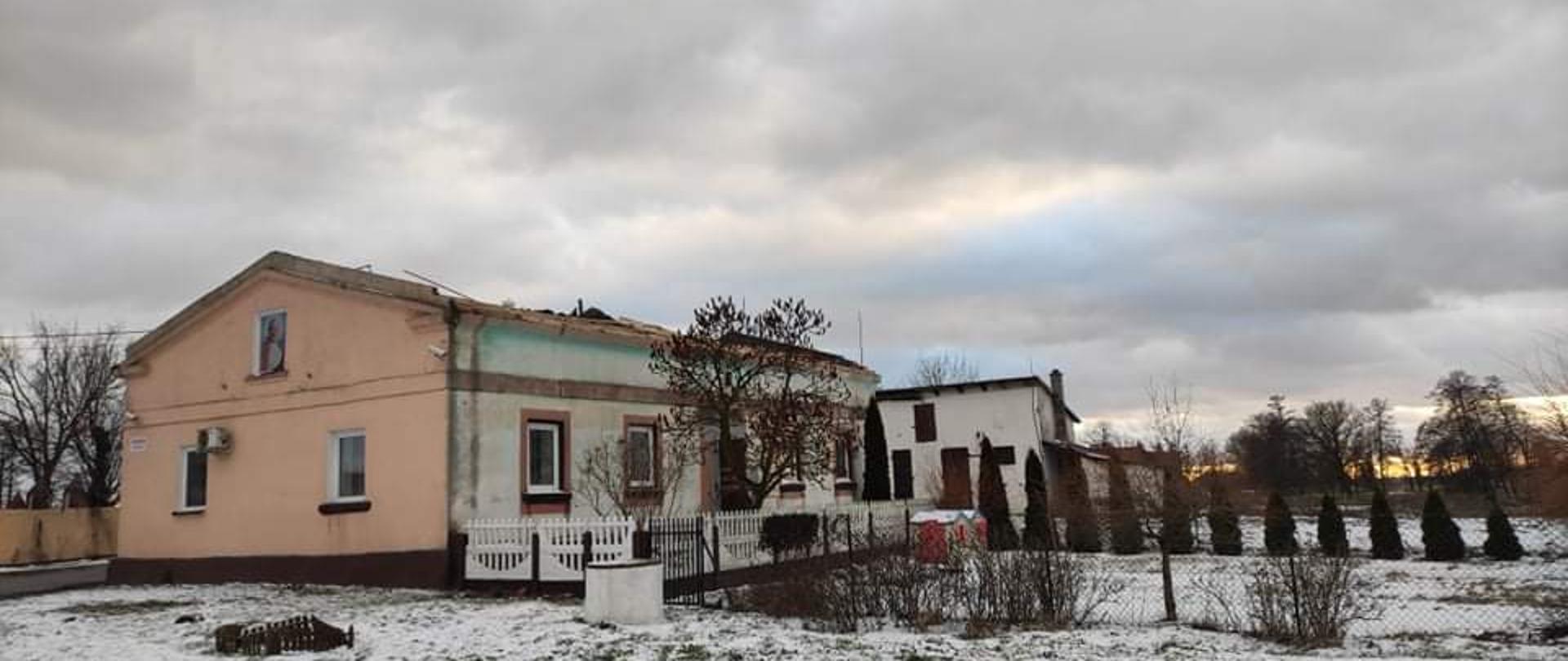 Zdjęcie przedstawia budynek z zerwanym dachem