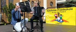 Prezentuje się uczeń klasy akordeonu . Jarosława Kloca- Wojciech Grasza. W tle kościół.
