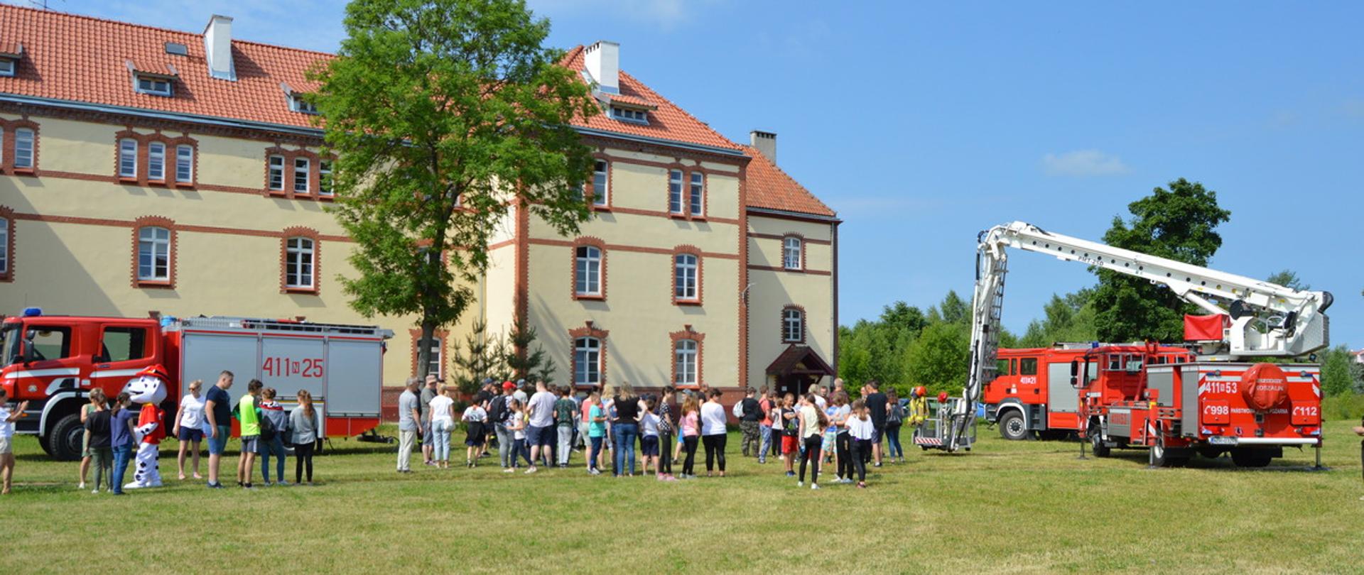 Na boisku przed szkołą, dzieci przy samochodach strażackich.