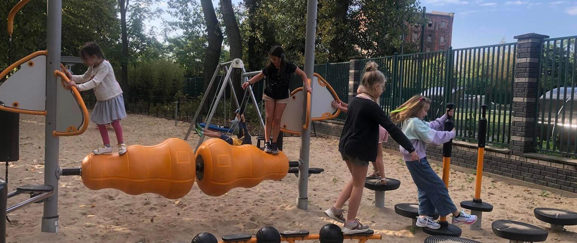 Dzieci bawią się na urządzeniach w siłowni w parku