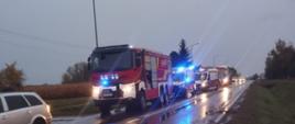 Na zdjęciu w porze wieczornej na drodze w której doszło do wypadku stoją zaparkowane auta służb ratowniczych na sygnałach. W tle na drodze widać porozrzucane odłamki aut.