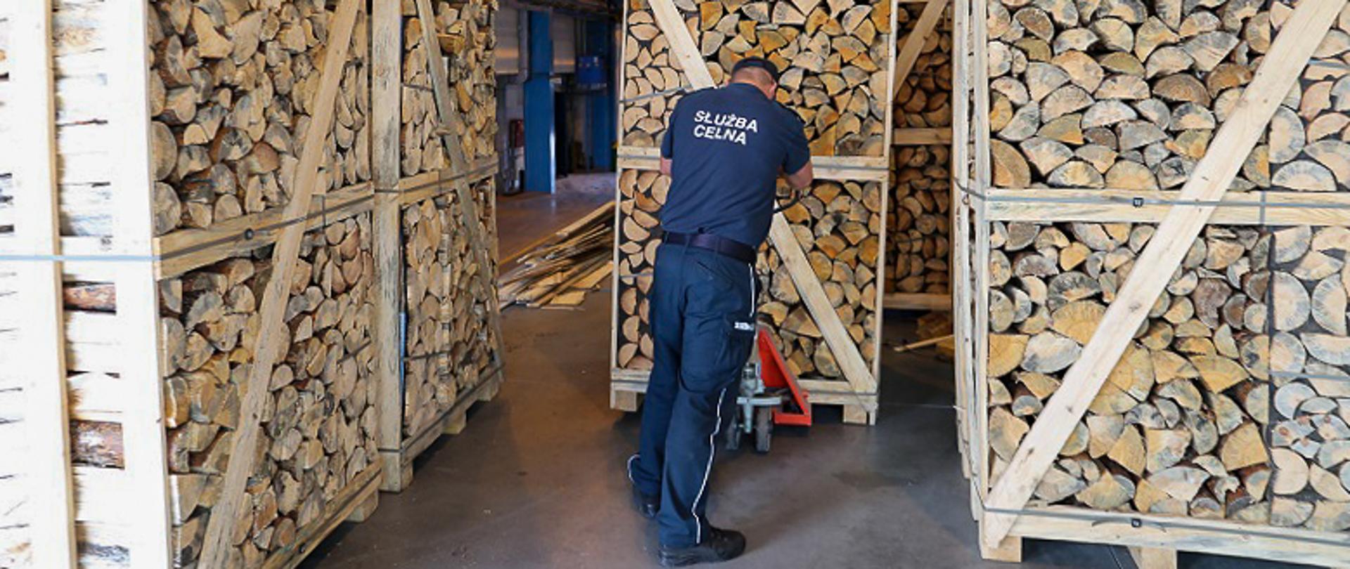 Funkcjonariusz KAS przewozi palety z drewnem opałowym, w którym ukryte są papierosy