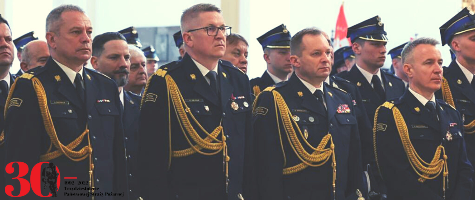 Komendant główny PSP wraz z zastępcami i innymi strażakami stoją w ławach kościelnych podczas mszy świętej