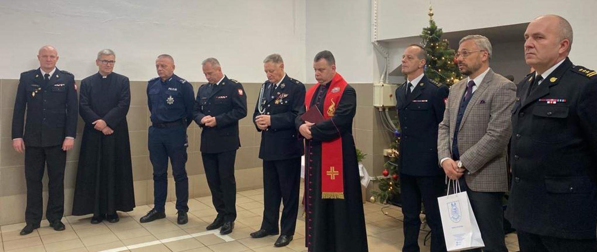 Podczas spotkania Wigilijnego w Komendzie Powiatowej Państwowej Straży Pożarnej w Rypinie ksiądz kanonik Mariusz Stasiak odmawia wspólną modlitwę ze zgromadzonymi funkcjonariuszami, druhami oraz przybyłymi gośćmi.