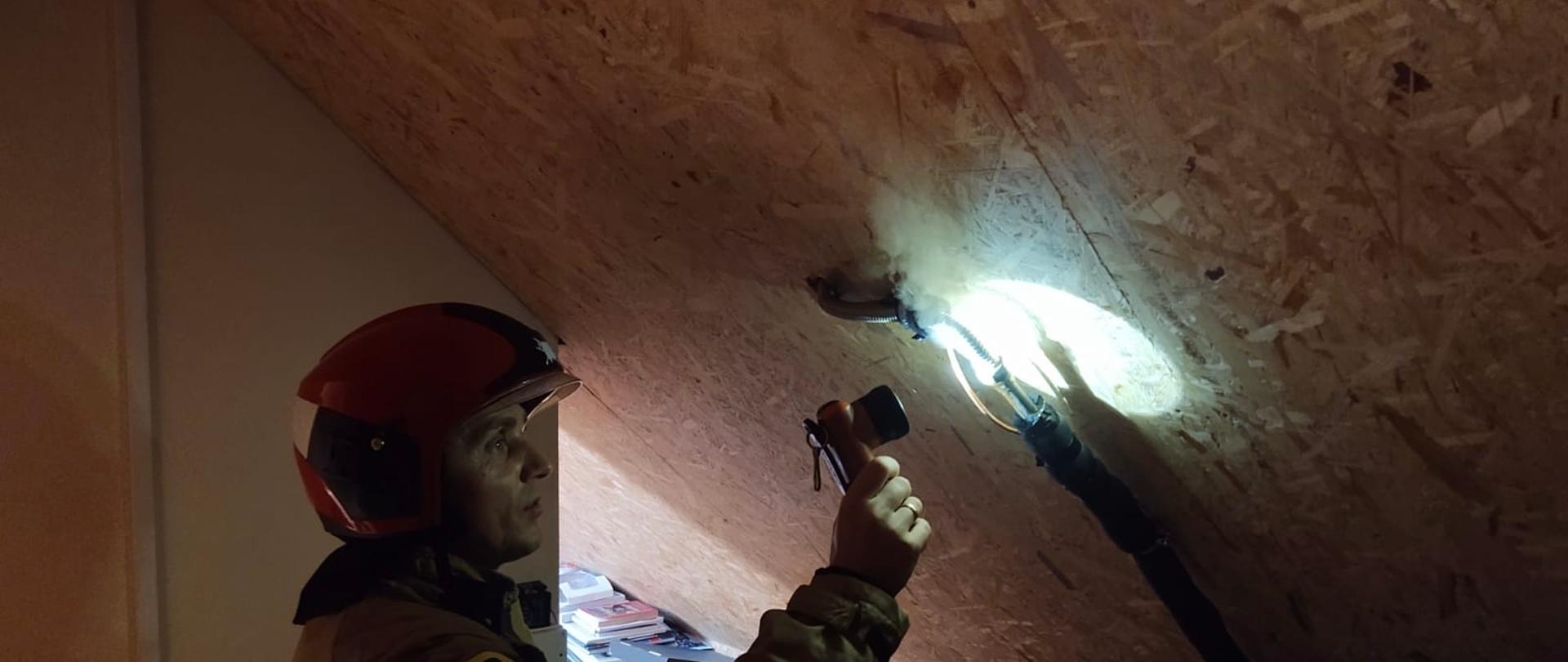 Strażak oświetla miejsce nieszczelności.