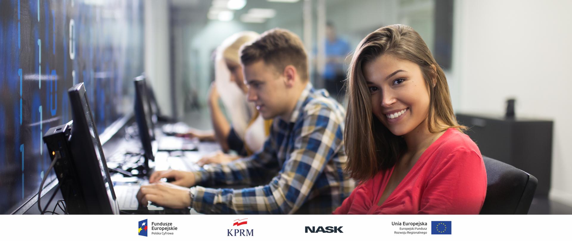 Na zdjęciu nowoczesna sala informatyczna, w niej młodzi uśmiechnięci ludzie korzystający z komputerów 