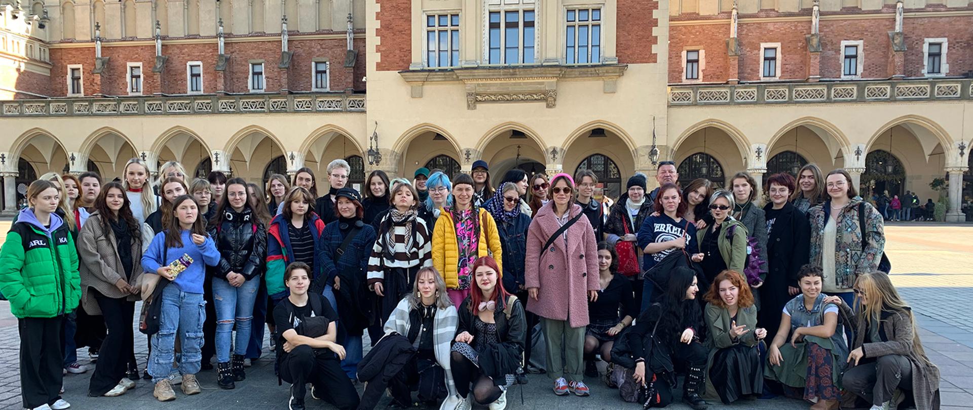 Zdjęcie grupowe przedstawiające uczniów i wychowawców szkoły na tle sukiennic w Krakowie.