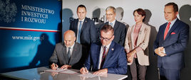 Podpisanie dokumentów z powiatem bieszczadzkim:
Przy stole umowę podpisują (od lewej): Starosta Bieszczadzki Marek Andruch i Podsekretarz Stanu w MIiR Adam Hamryszczak. Za nimi stoją (od lewej): Wicestarosta Bieszczadzki Artur Woźny, Minister Inwestycji i Rozwoju Jerzy Kwieciński, Wicewojewoda Podkarpacki Lucyna Podhalicz, Marszałek Województwa Podkarpackiego Władysław Ortyl.