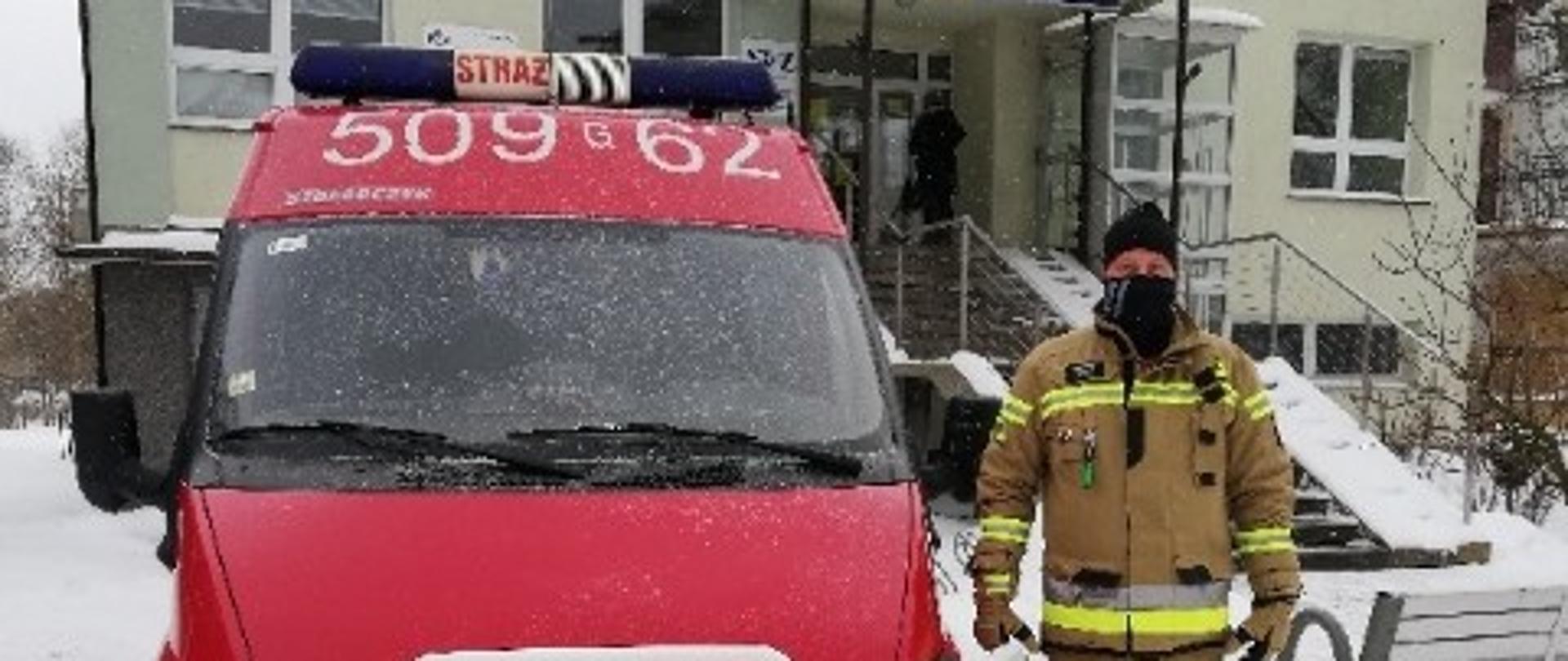 Zdjęcie przedstawia samochód ochotniczej straży pożarnej stojący pod punktem szczepień.