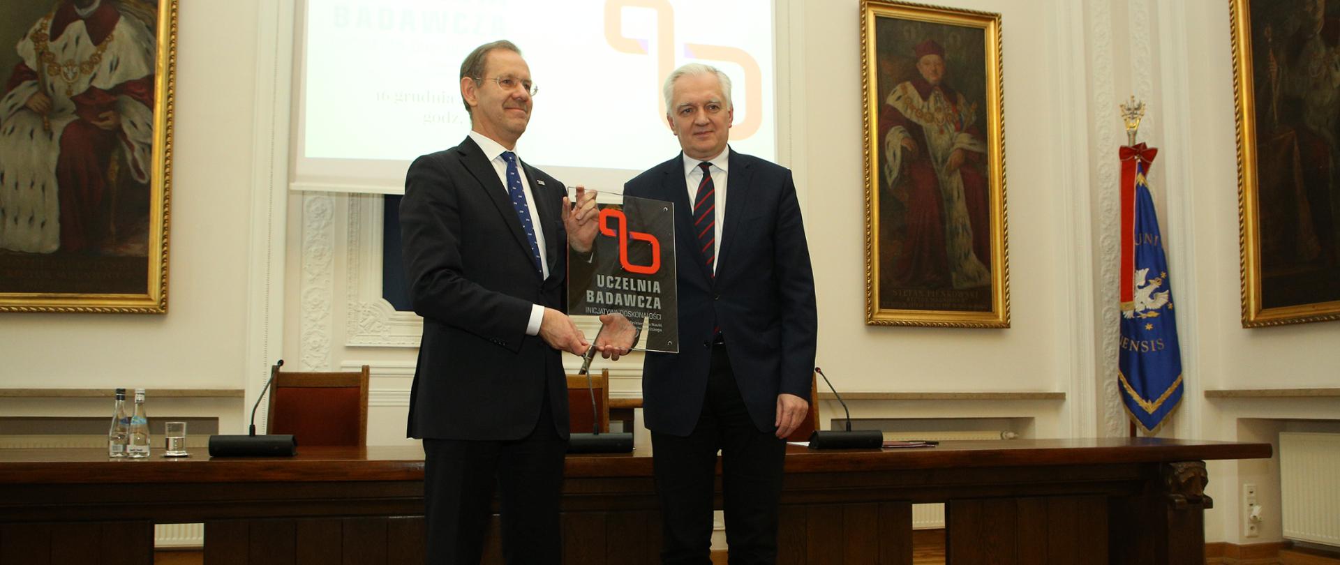 przed pulpitem stoją wicepremier Jarosław Gowin i rektor UW M. Pałys