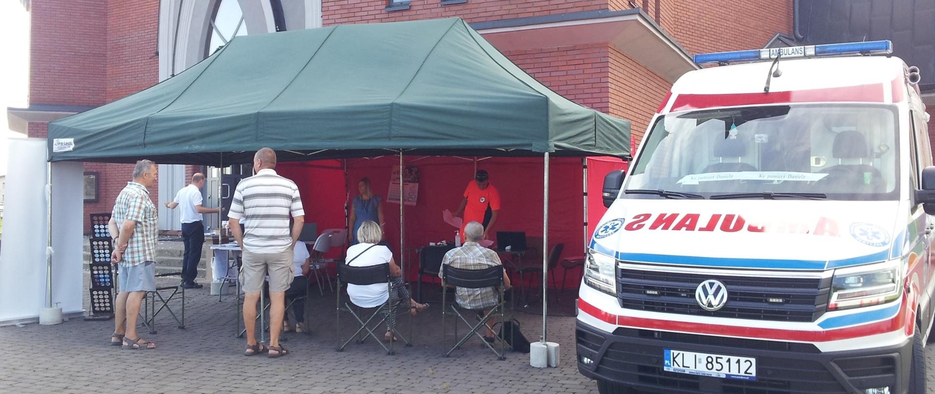 Namiot pod którym czekają ludzie na przyjęcie szczepionki. Z prawej karetka pogotowia.
