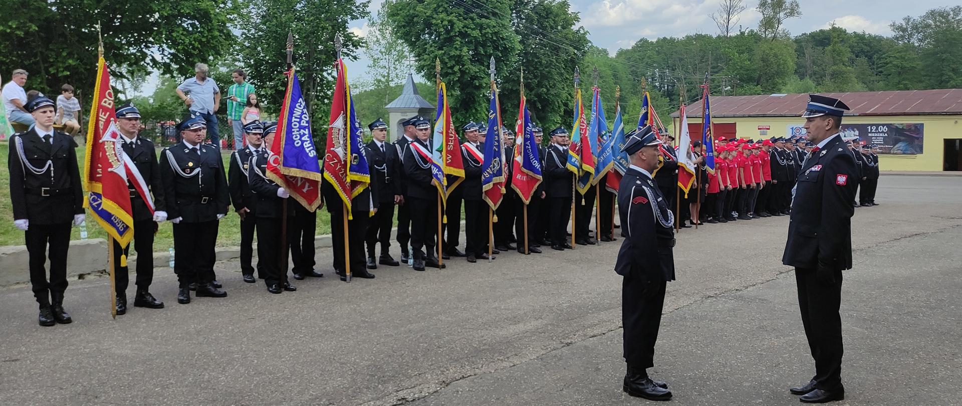 100-lecie jednostki Ochotniczej Straży Pożarnej w Niecieczy - na placu przed strażnicą w Niecieczy, trwają uroczystości jubileuszowe. Dowódca uroczystości składa meldunek o rozpoczęciu uroczystości. W tle Strażacy OSP w mundurach, ze sztandarami OSP.