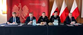 Zastępca komendanta głównego PSP, świętokrzyski komendant wojewódzki oraz przedstawiciele władz samorządowych siedzący przy stole prezydialnym.
