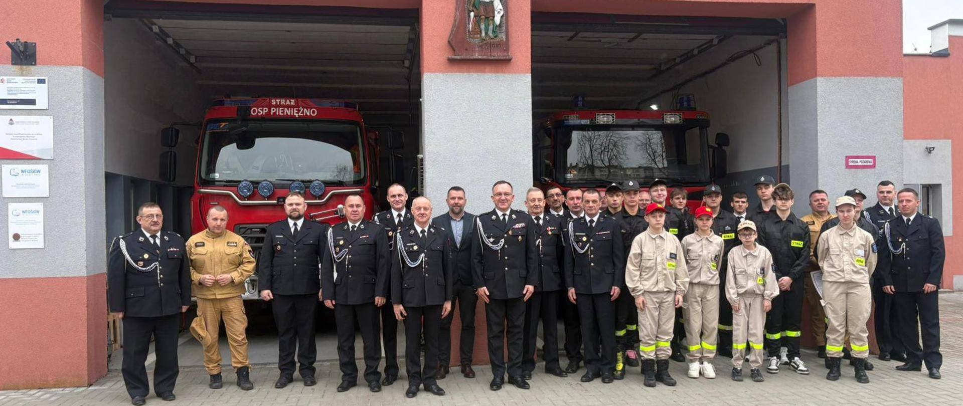 Zdjęcie grupowe przed remizą OSP. Na zdjęciu duża grupa strażaków ochotników oraz młodzieży.