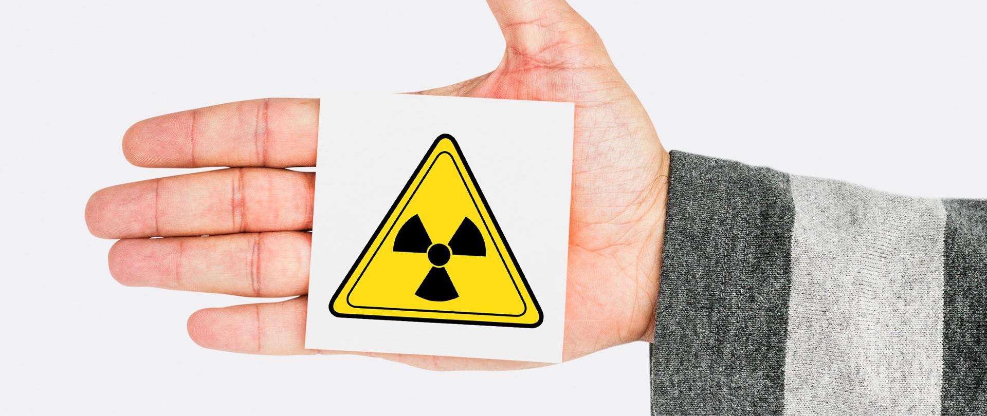 Na dłoni kwadratowy znak - symbol promieniowania radioaktwnego
