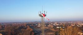 Dwóch strażaków zawiesza flagę narodową na maszcie antenowym kratownicowym, w tle panorama dzielnicy Stradom w Częstochowie