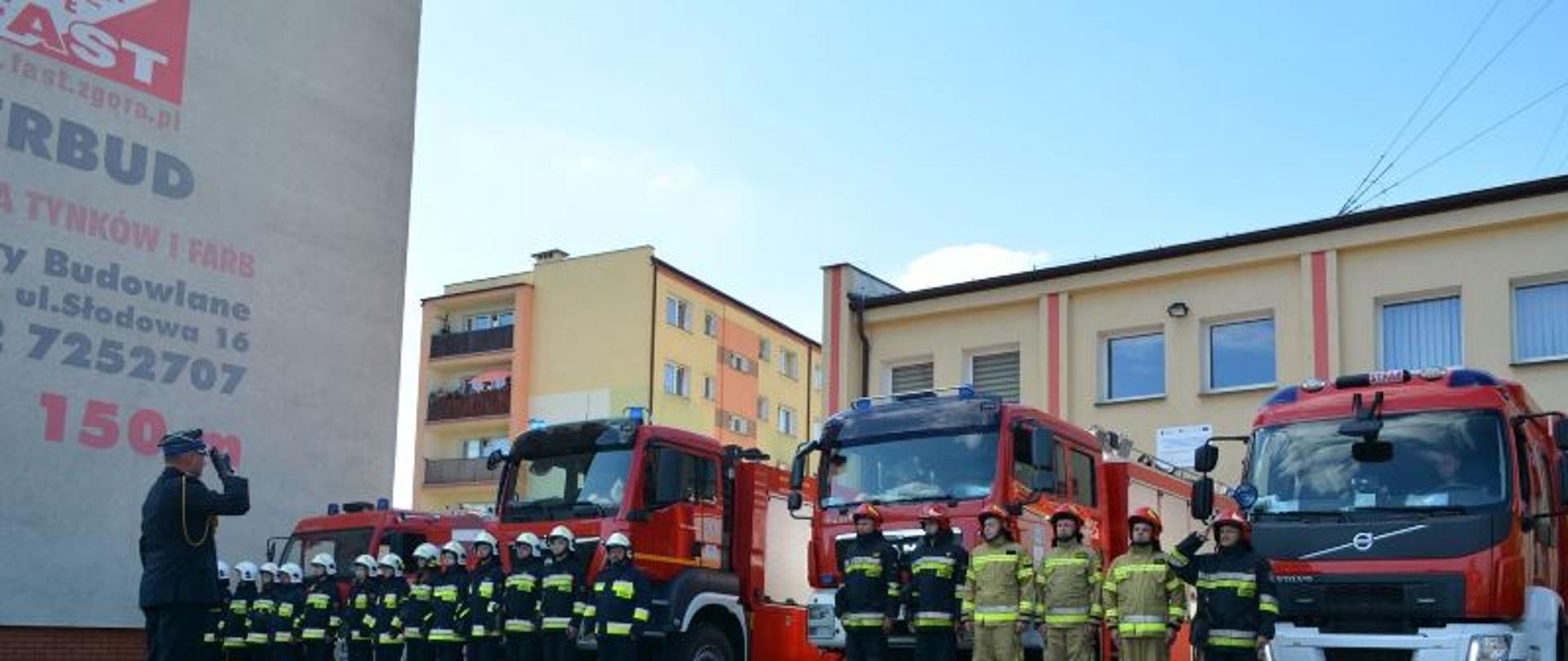 Uroczysty apel w hołdzie powstańcom warszawskim. Punktualnie o godzinie "W" czyli 17:00 strażacy z Jednostki Ratowniczo - Gaśniczej oraz druhowie z jednostki OSP Krotoszyn ustawieni w szyku na tle pojazdów pożarniczych przed budynkiem komendy powiatowej oddali hołd powstańcom. Ceremonii przewodniczył Komendant Powiatowy, który stoi frontem do szyku i wraz z dowódcami pododdziałów oddaje honor na część powstańców. Komendant Powiatowy ubrany jest w mundur galowy natomiast strażacy w szyku w ubrania bojowe oraz hełmy strazackie.