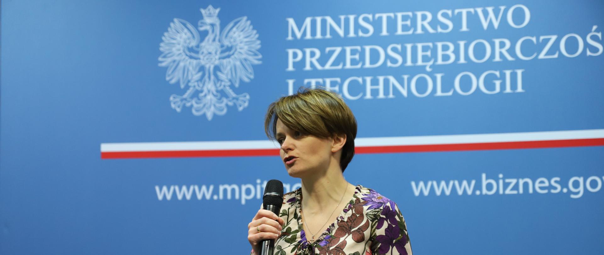 Minister przemawia na tle ścianki MPiT