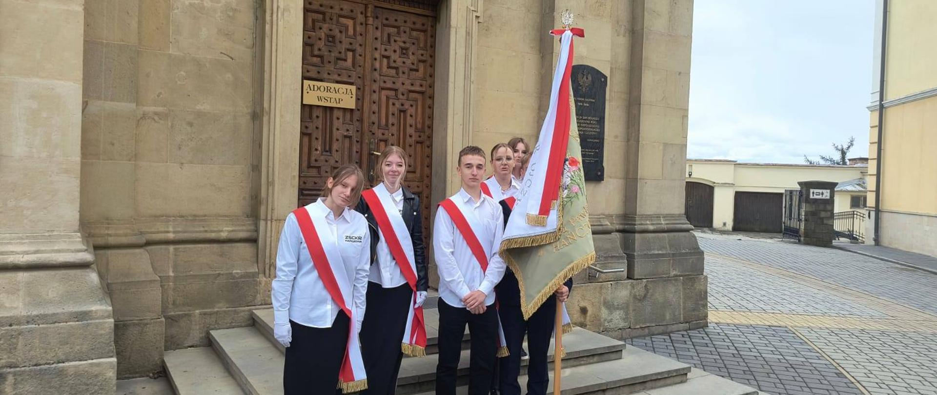 Poczet sztandarowy pozuje przed wejściem do kościoła.