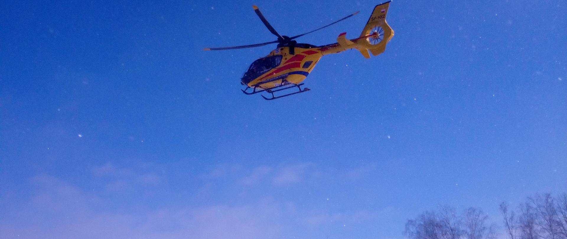 na zdjęciu widać śmigłowiec Lotniczego Pogotowia Ratunkowego, który startuję z zaśnieżonego pola.