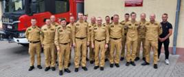 Zdjęcie grupowe strażaków na tle budynku komendy.