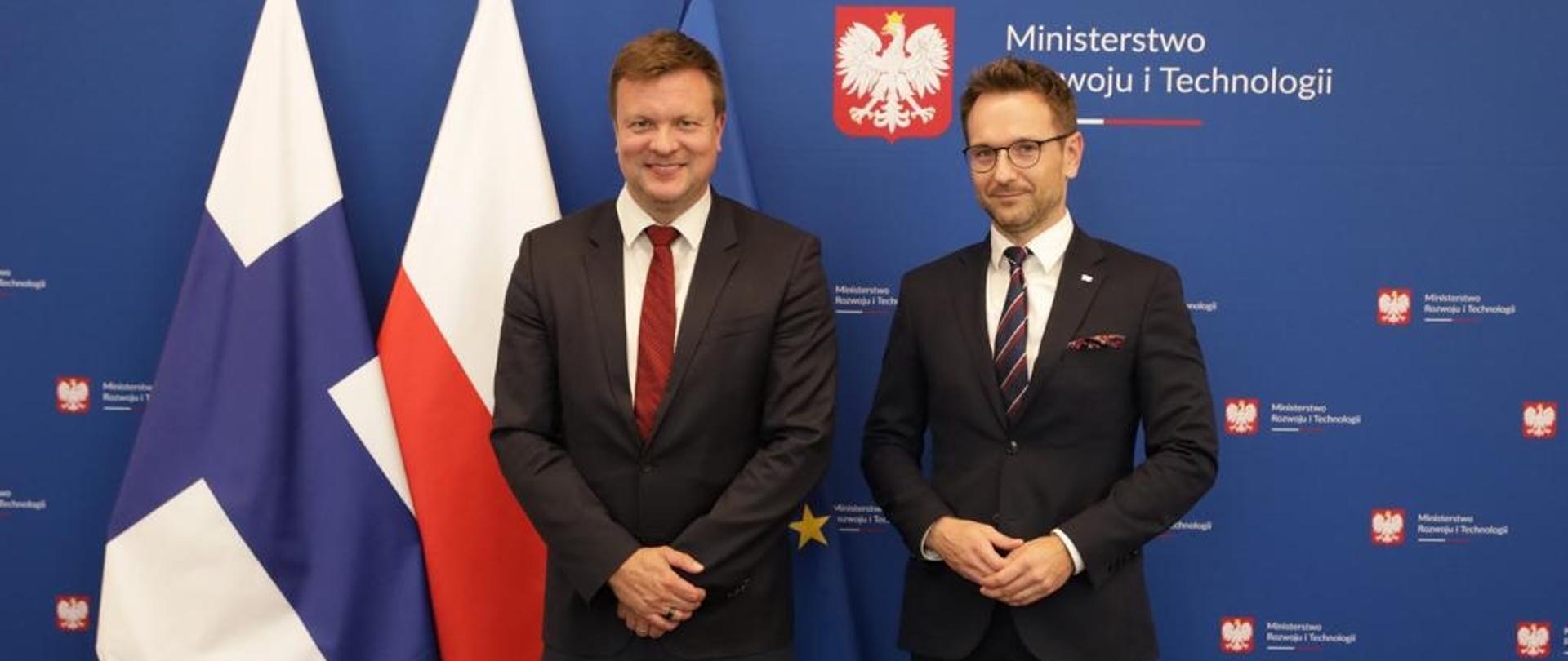 Minister rozwoju i technologii Waldemar Buda i minister współpracy rozwojowej i handlu Finladii Ville Skinnari, za plecami ministrów stoją flagi Polski, Finlandii i UE oraz banner MRiT
