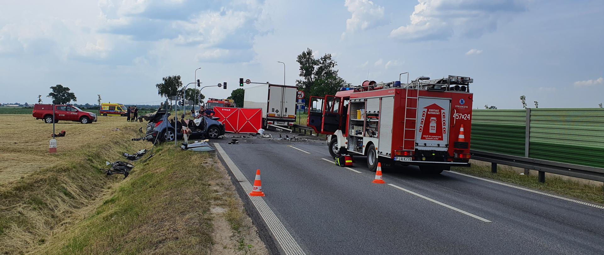 Wozy strażackie stojące na drodze, rozbity samochód osobowy