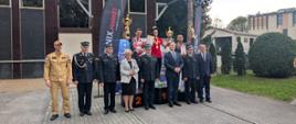 W dwóch rzędach stoją funkcjonariusze Państwowej Straży Pożarnej, oraz zaproszenie oficjele w pierwszym rzędzie, w drugim rzędzie na podium stoją sportowcy, na szyjach mają zwieszone medale, a w rękach dyplomy. Z tyłu widać wspinalnię.
