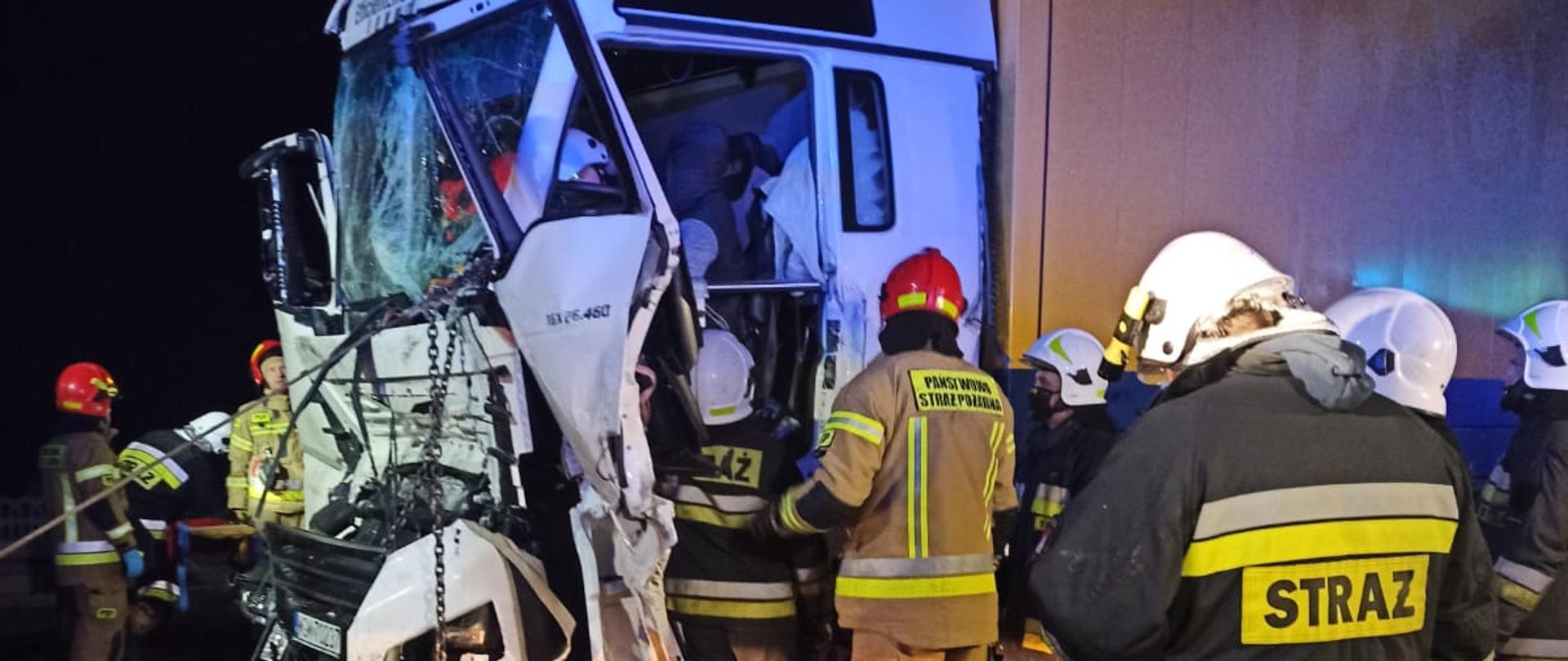 Zdjęcie przedstawia strażaków podczas działań ratowniczo-gaśniczych przy wypadku samochodów ciężarowych