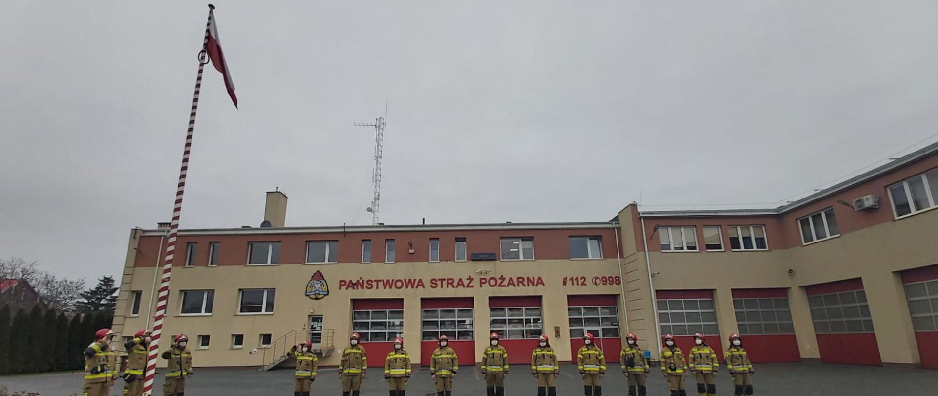 Zdjęcie przedstawia strażaków podczas oddawania honorów fladze państwowej
