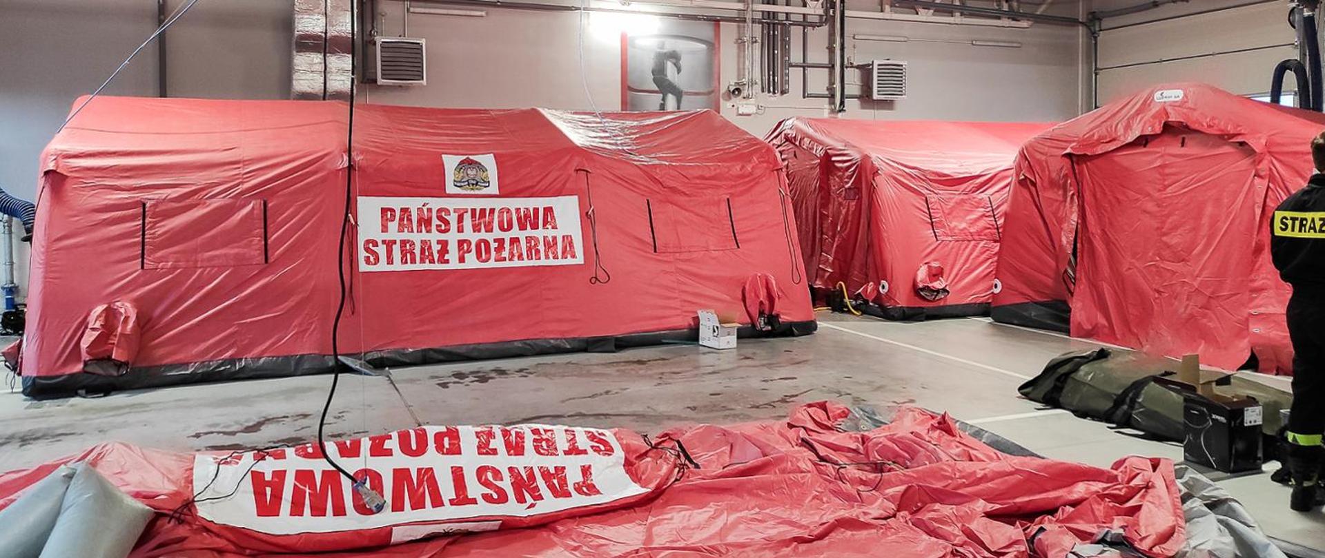 Zdjęcie przedstawia 3 namioty pneumatyczne koloru czerwonego. Na namiotach widoczny jest napis Państwowa Straż Pożarna